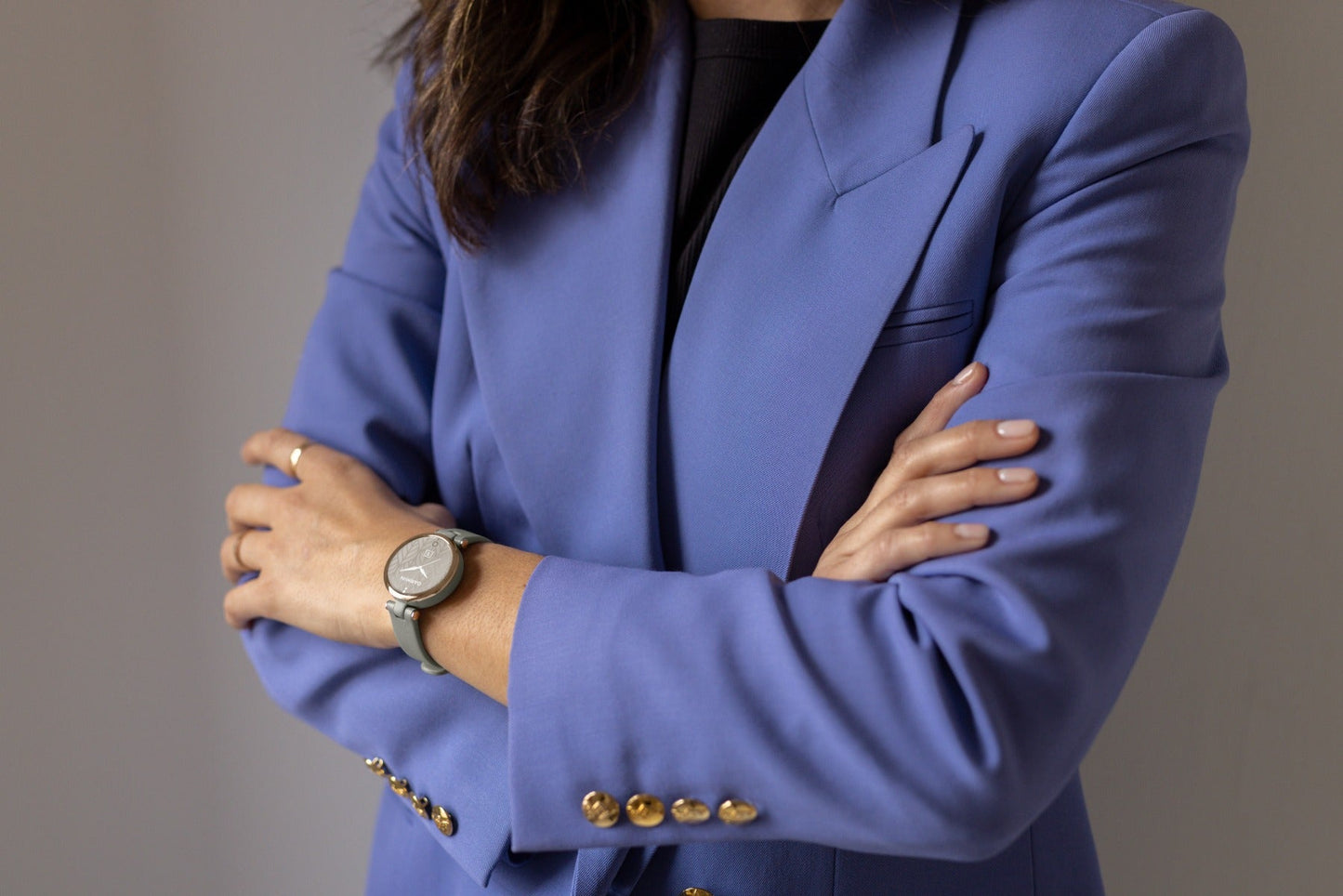 Garmin Lily Classic Edition smartwatch with gray strap on a wrist, worn by a person in a blue blazer.