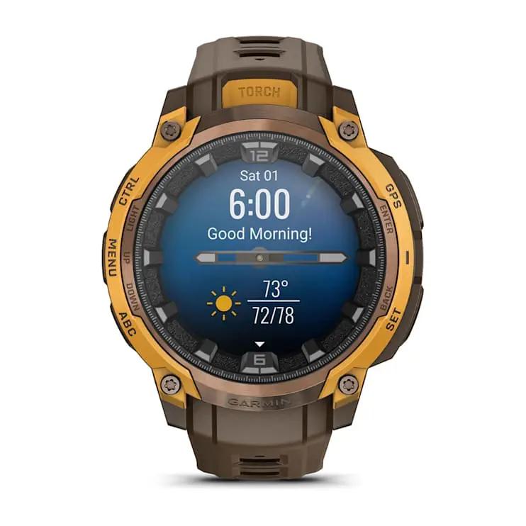Garmin Instinct Crossover AMOLED smartwatch with brown strap and orange bezel, displaying time and weather.