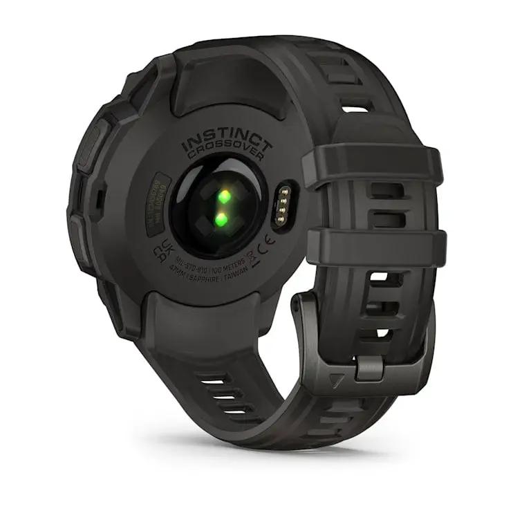 Garmin Instinct Crossover AMOLED smart watch, black rugged strap, back view with green charging LEDs.
